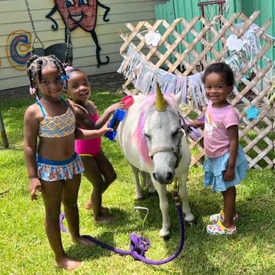 Small children playing with a pony.